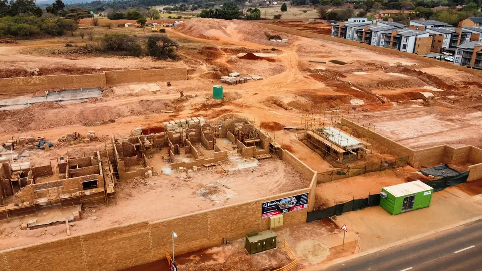 Wide aerial view across the active iQ Bronberg construction site from Ajax Avenue